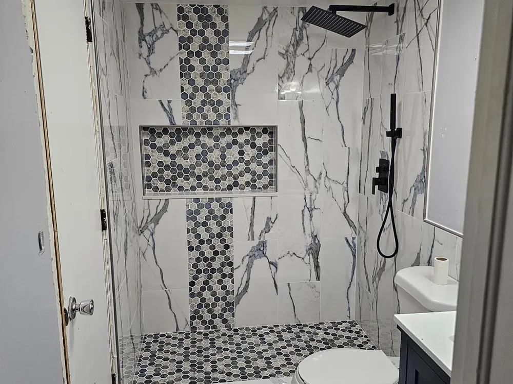 Completed walk-in shower with patterned tile accent and black fixtures