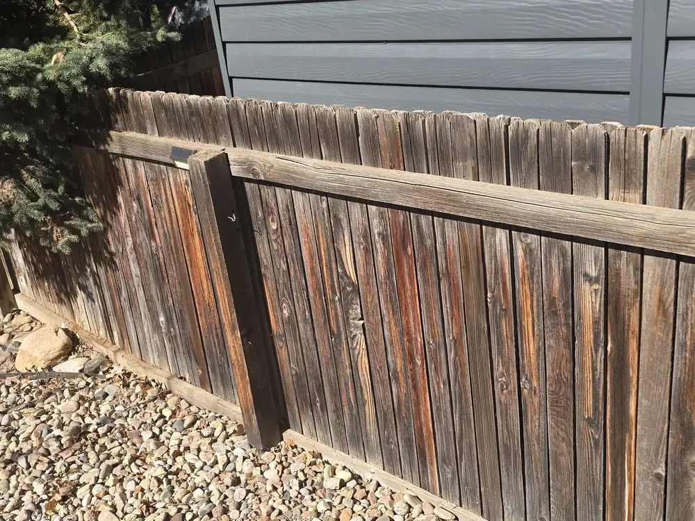Before view of the same weathered wood privacy fence